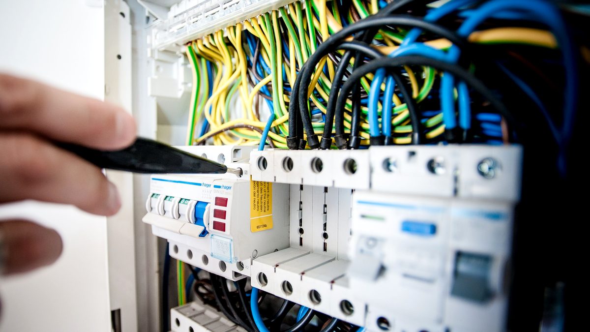 Elektryk pracujący przy rozdzielnicy i zabezpieczeniach elektrycznych