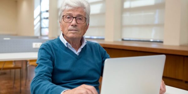 Senior kontynuujący pracę przy komputerze po osiągnięciu wieku emerytalnego